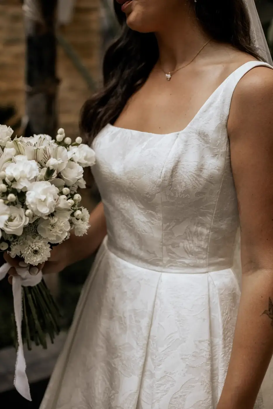 Detalle del vestido de novia de Rhianna y su ramo de flores blancas