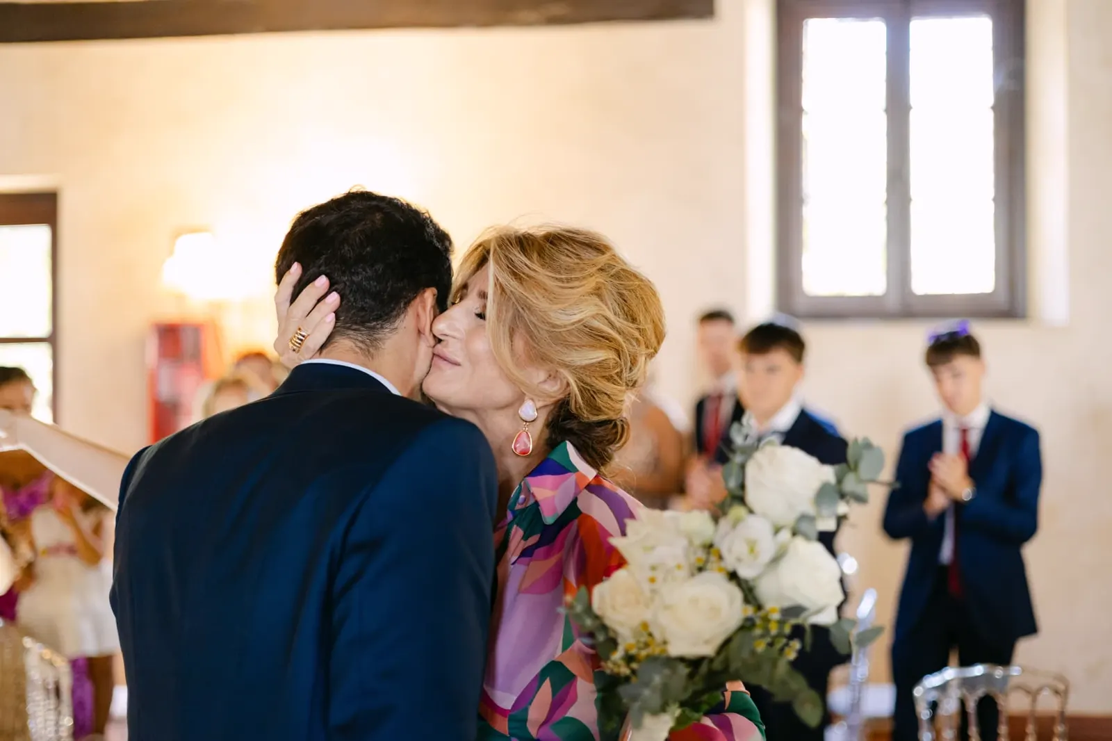 Luis recibiendo un beso de su madre en el salón de la hacienda