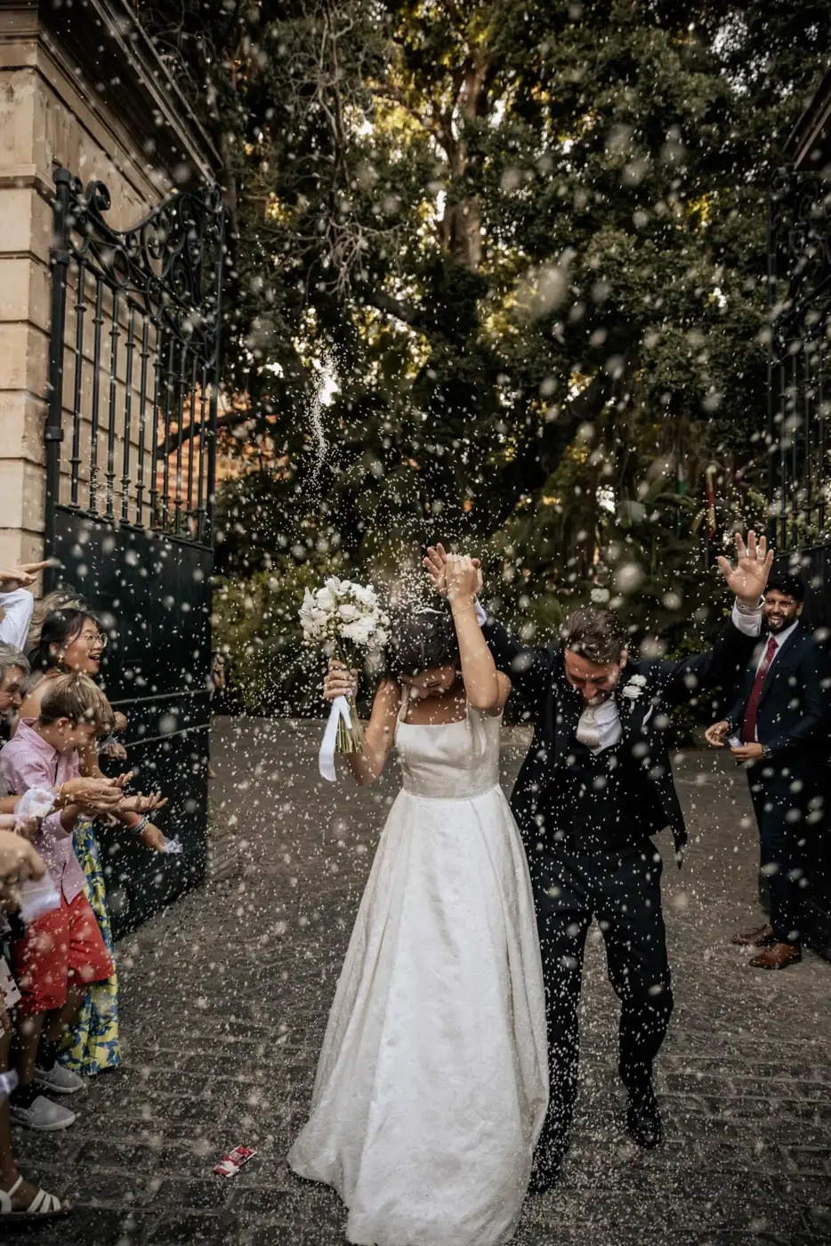 Rhianna y Javier saliendo entre lluvia de arroz rodeados de sus invitados