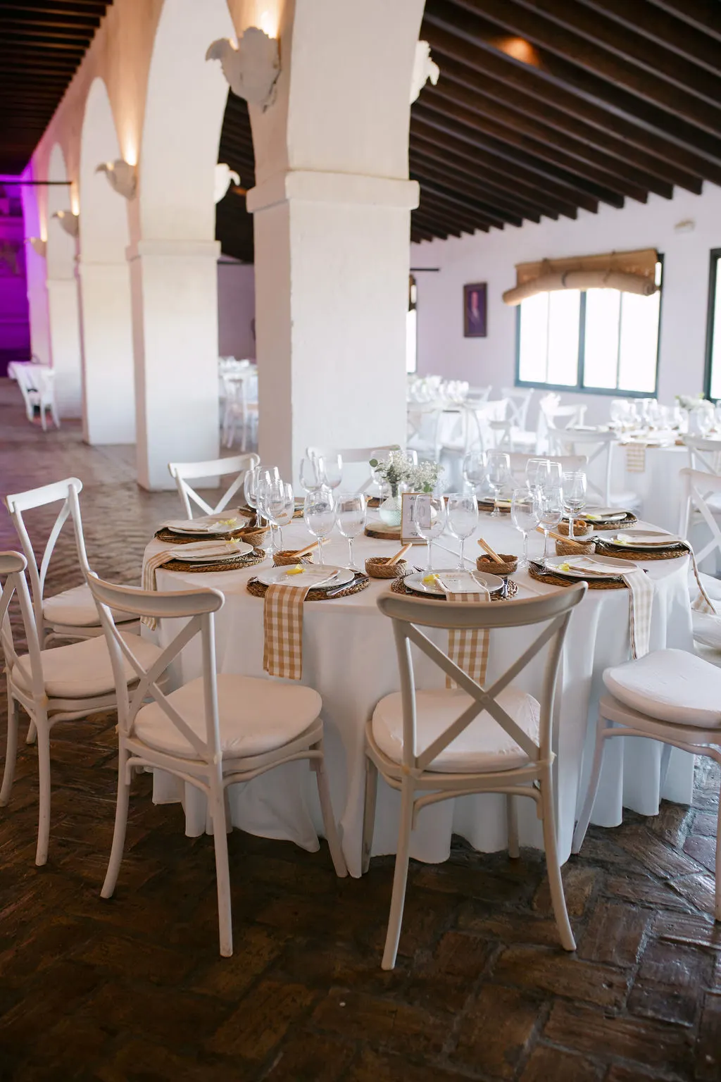 Mesa de banquete vestida de blanco bajo los arcos de Bodegas Barbadillo