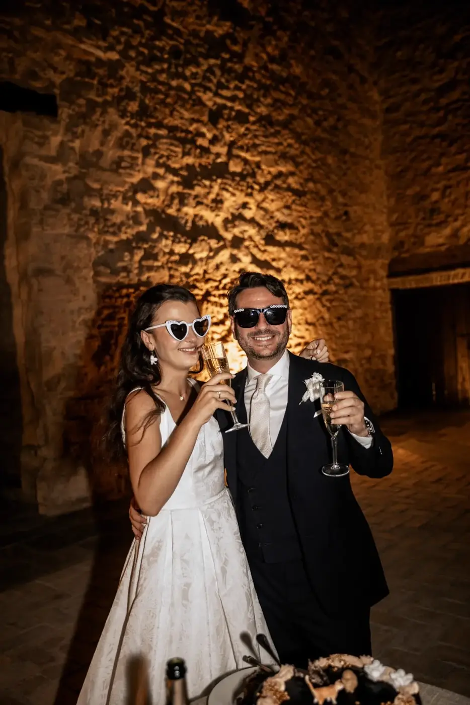 Rhianna y Javier brindando con gafas de Just Married junto a la tarta