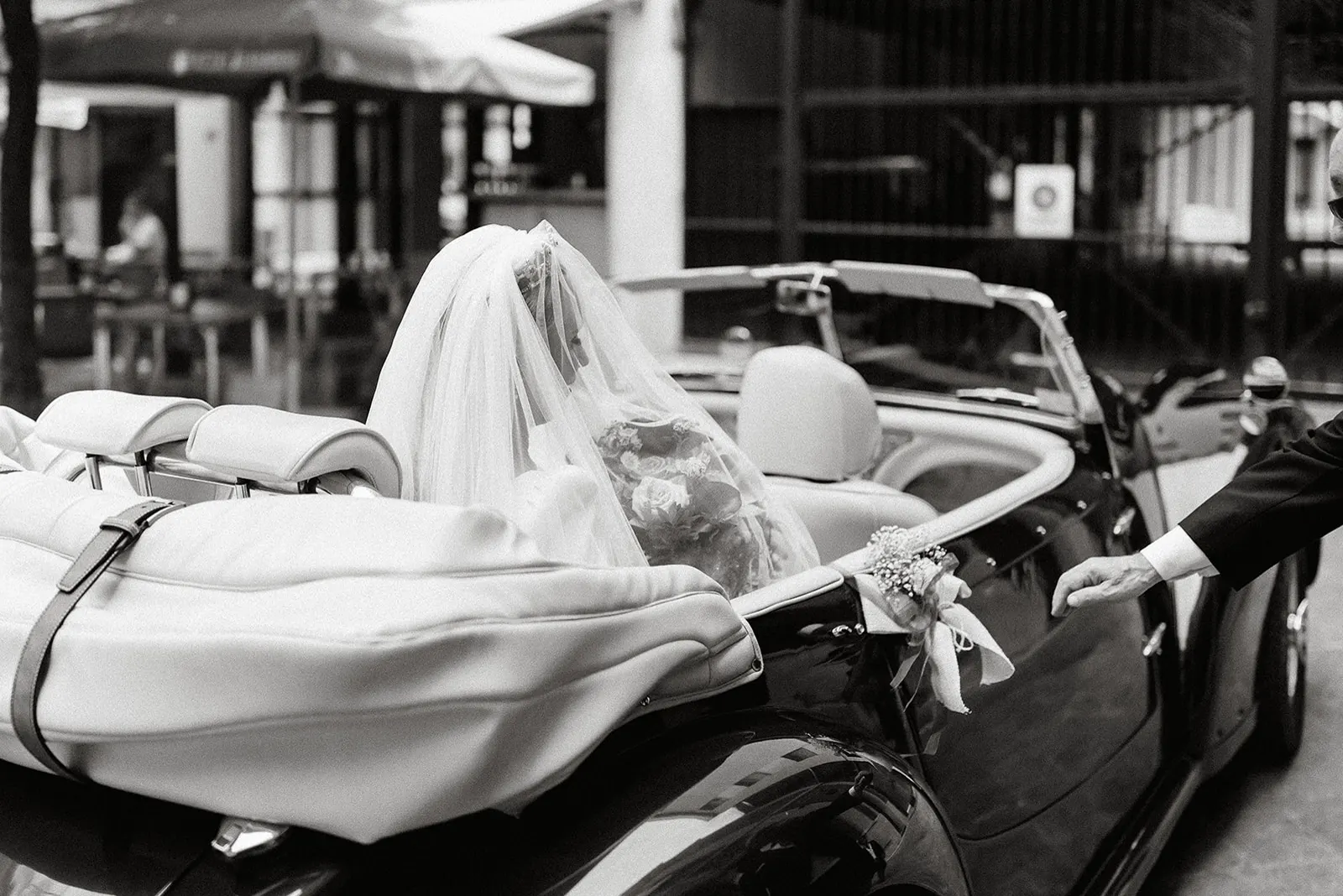 Luyza llegando a la iglesia en un coche clásico descapotable, en blanco y negro