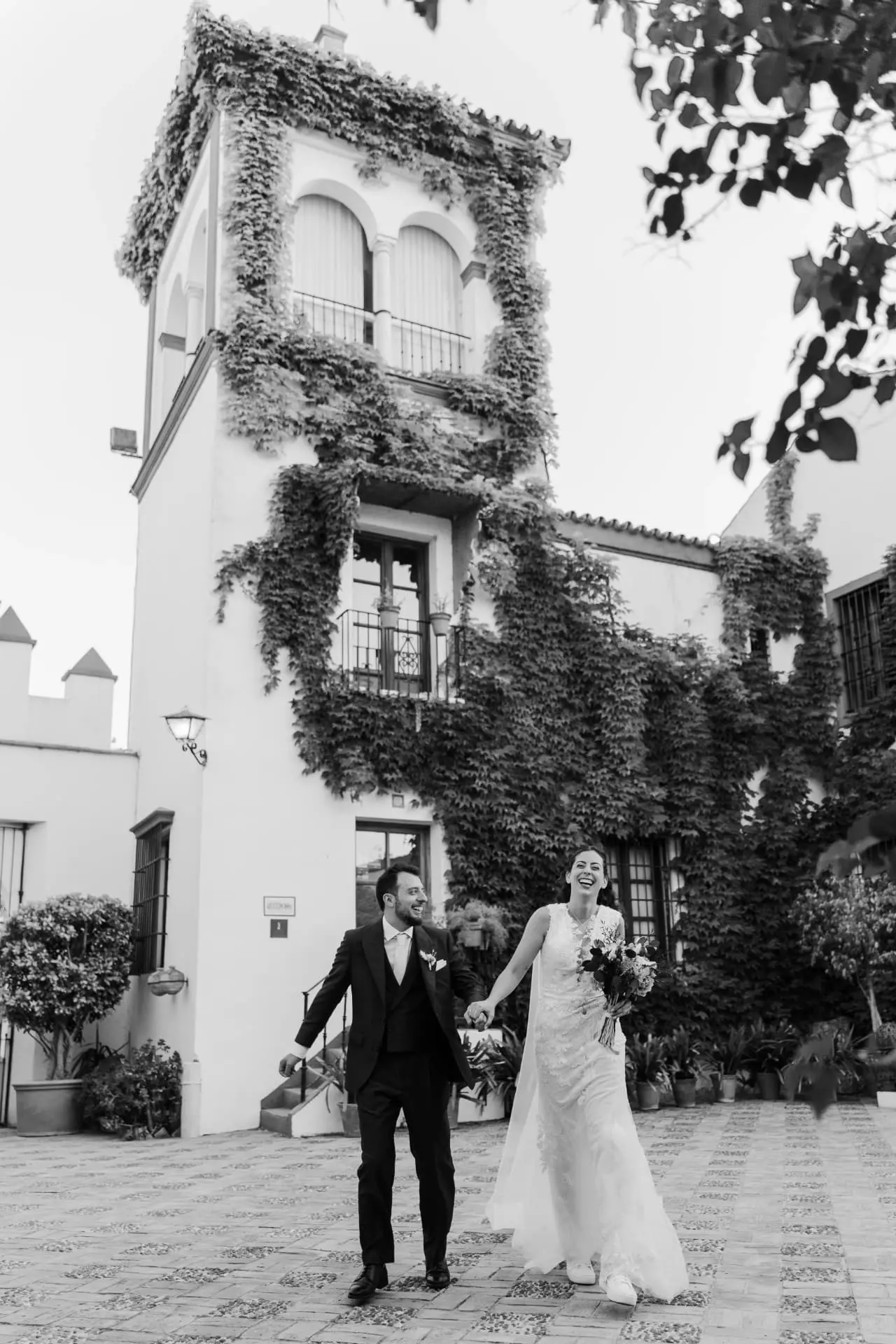 Ana y Manuel de la mano frente a la torre de la hacienda, en blanco y negro