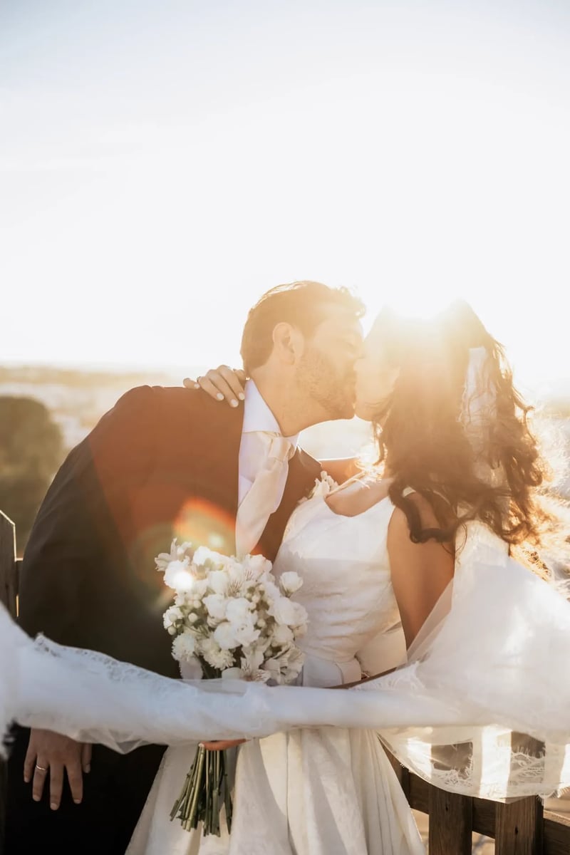 Rhianna y Javier besándose a contraluz al atardecer con el ramo blanco – boda organizada por Greta Weddings