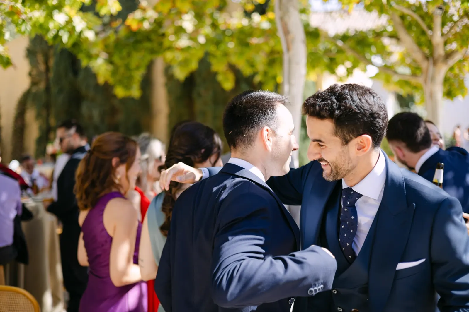 Luis abrazando a un invitado durante el aperitivo bajo los árboles