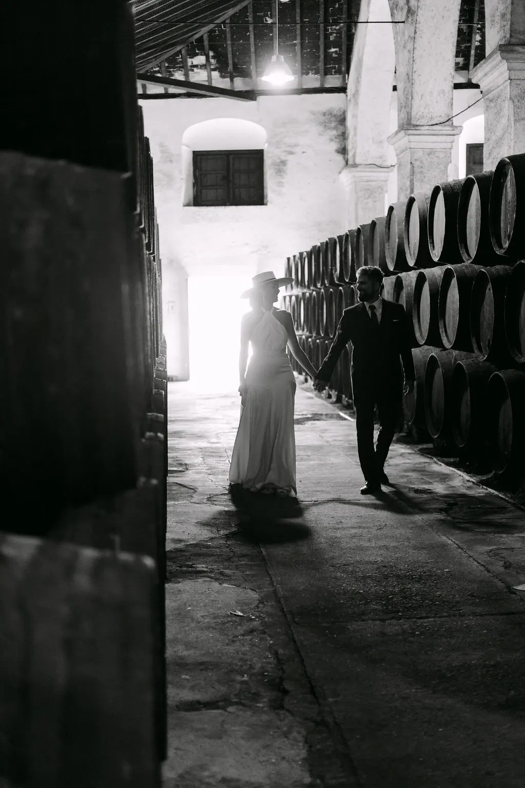 MªCarmen y Jose Miguel paseando de la mano entre las barricas de Bodegas Barbadillo, en blanco y negro