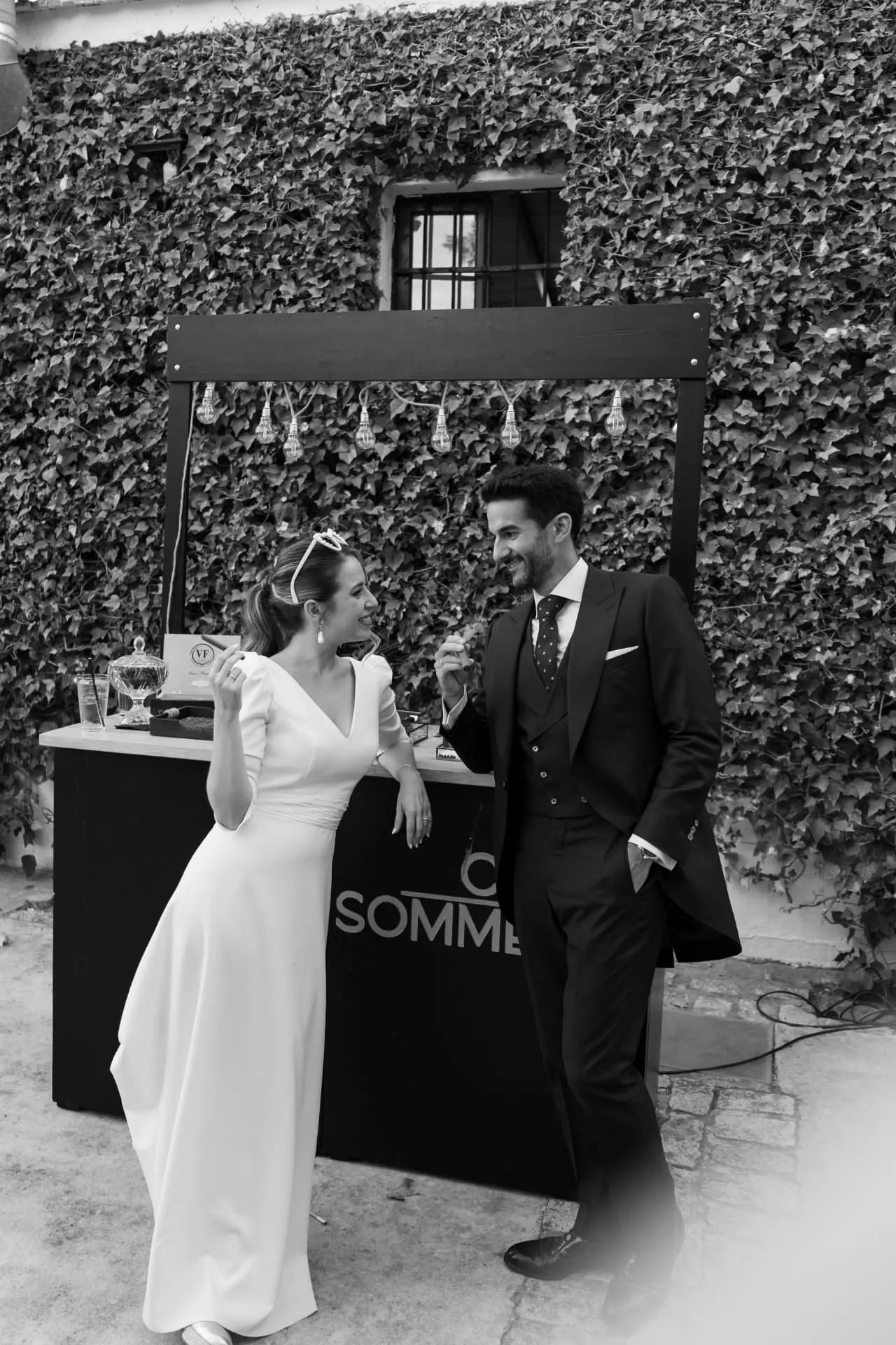 Aisha y Luis riendo junto al puesto de puros de la fiesta, en blanco y negro
