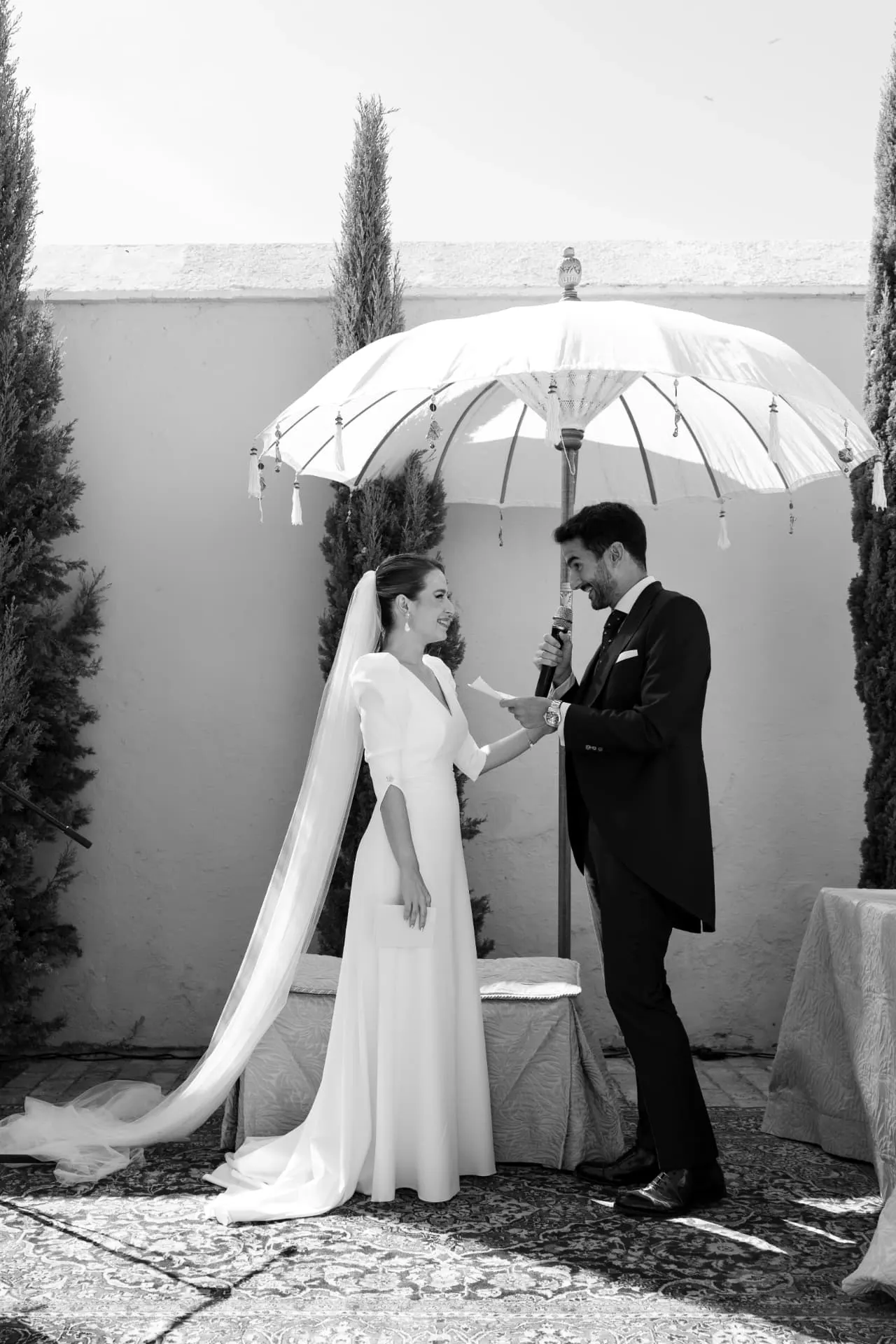 Aisha y Luis leyendo sus votos bajo una sombrilla blanca en el patio de la hacienda