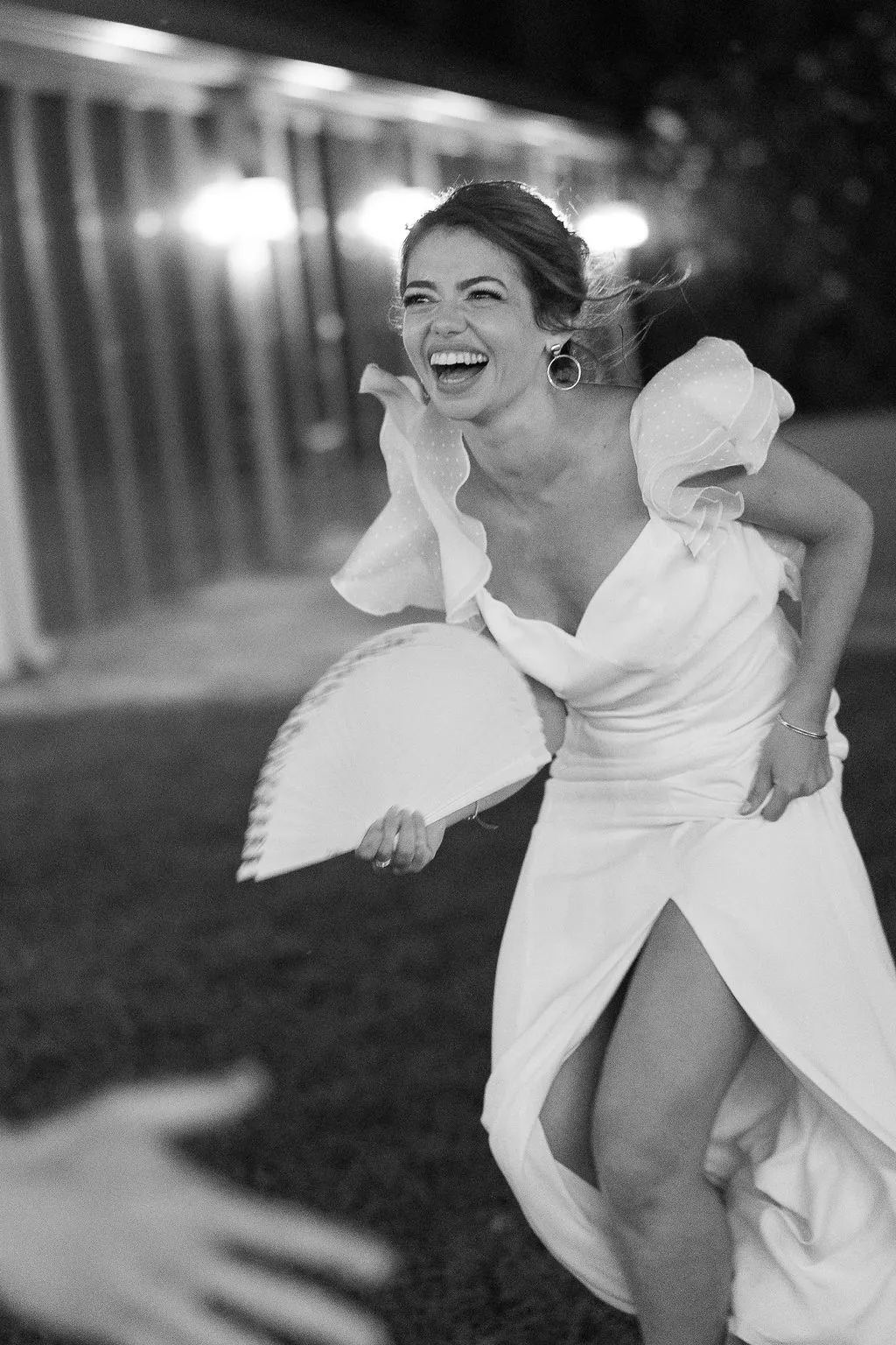 Julia riendo y bailando con un abanico en la fiesta, en blanco y negro