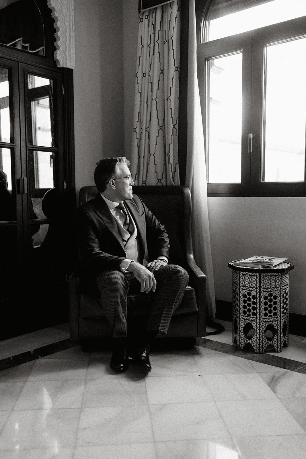 Fernando esperando junto a la ventana antes de la ceremonia, en blanco y negro