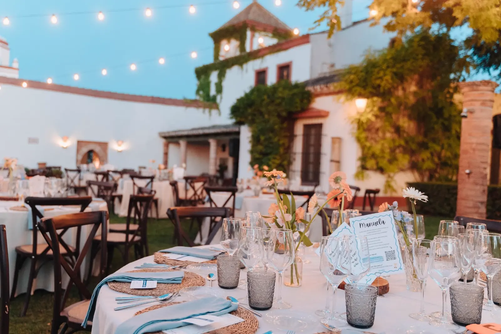 Mesa con minuta personalizada, cristalería y flores en tonos coral y azul