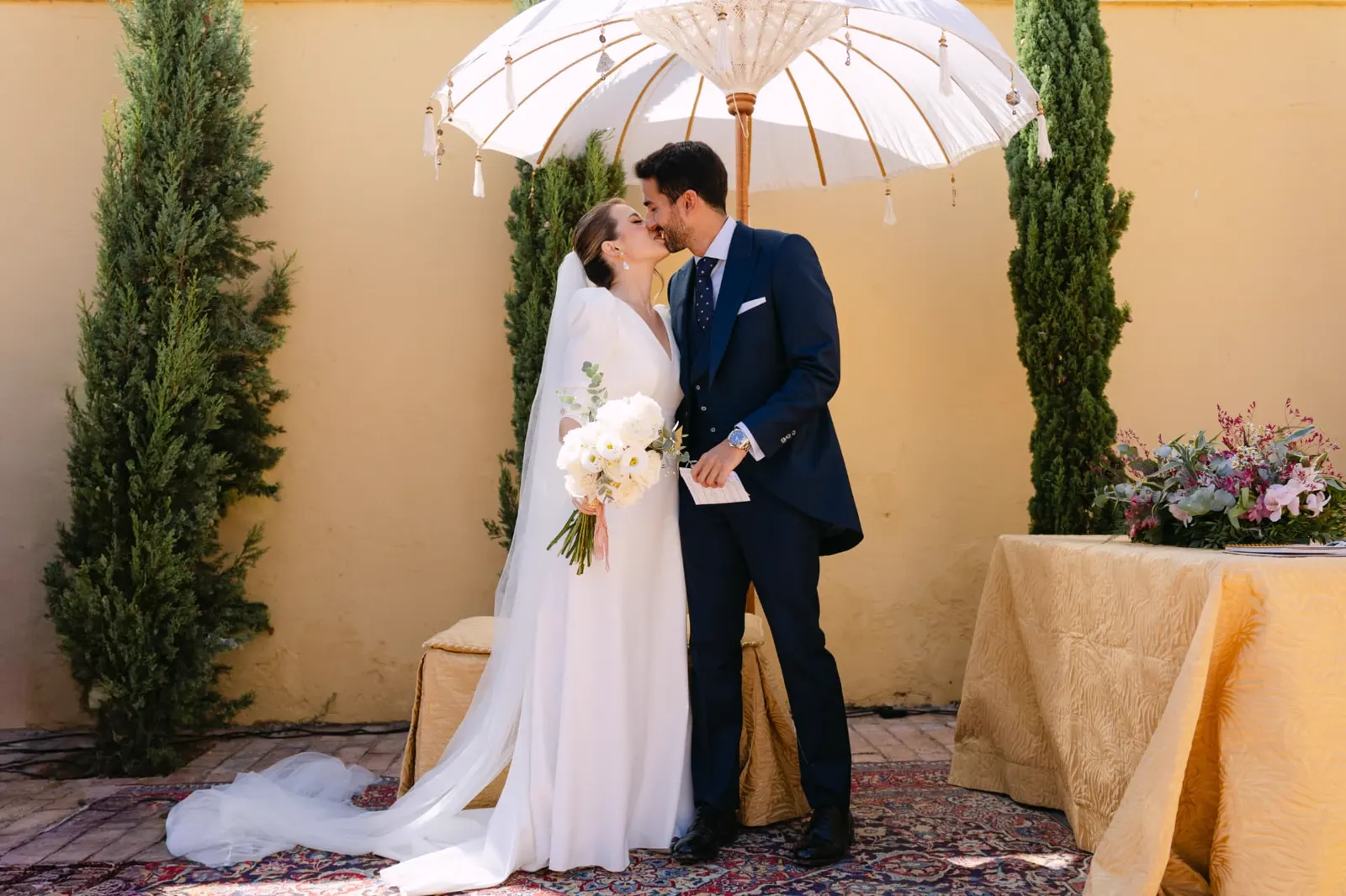 Aisha y Luis besándose bajo las sombrillas blancas de su ceremonia en Hacienda Clarevot