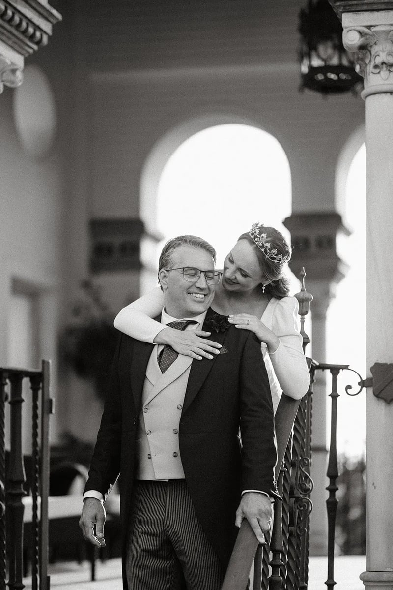 Luyza abrazando a Fernando en una galería del Hotel Alfonso XIII, en blanco y negro – boda organizada por Greta Weddings