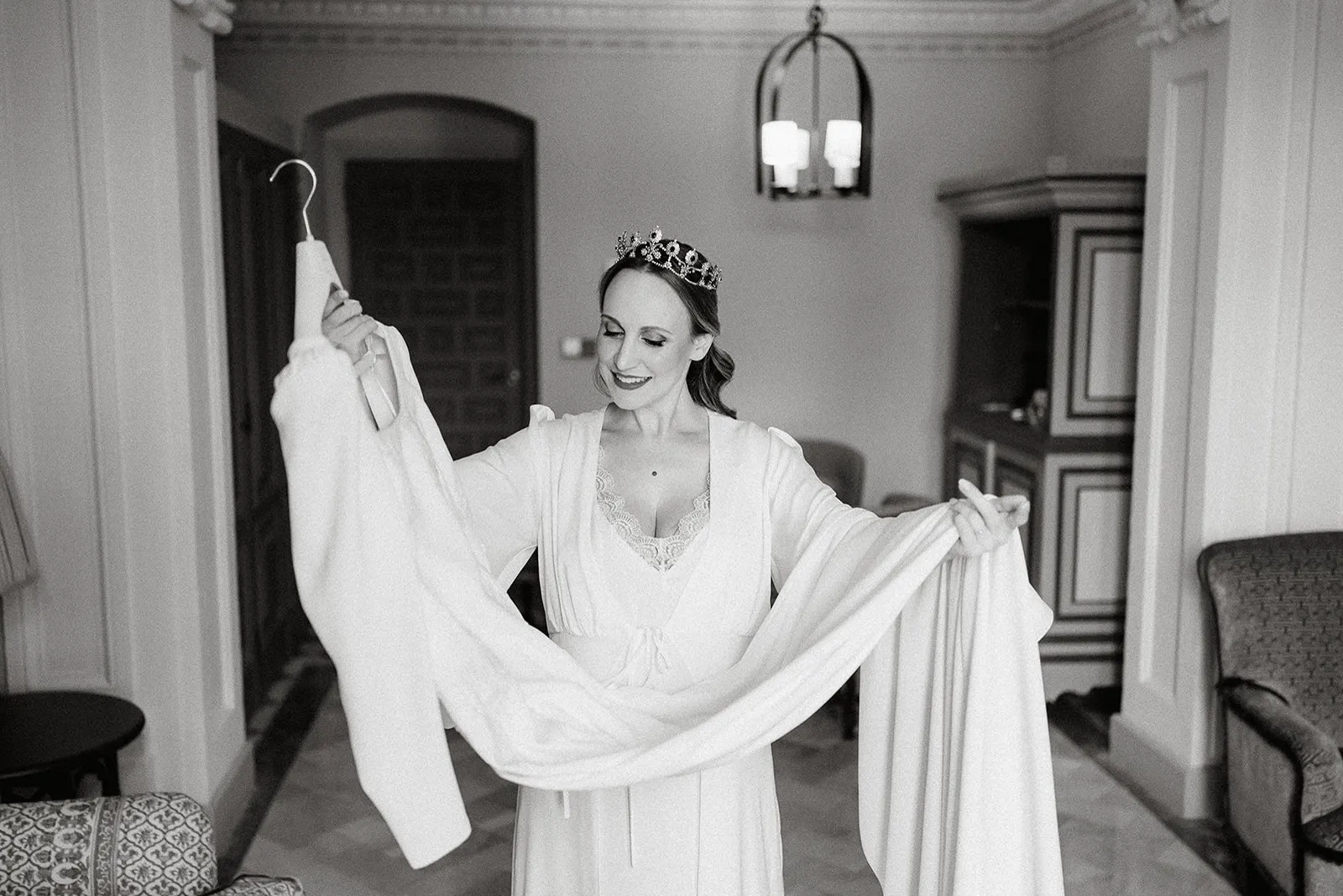 Luyza sosteniendo su vestido de novia antes de vestirse, en blanco y negro