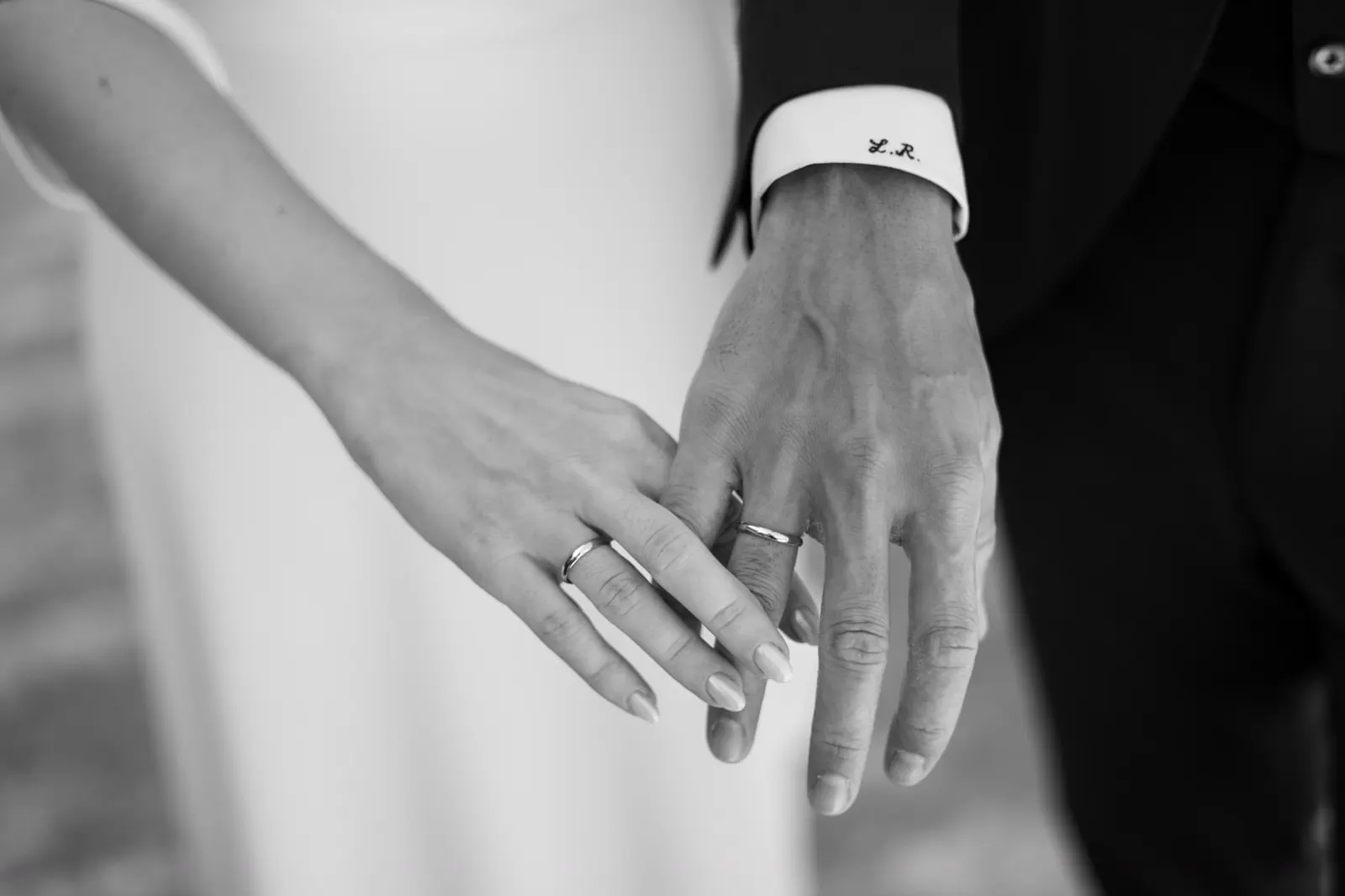 Detalle en blanco y negro de las manos de Aisha y Luis con sus alianzas