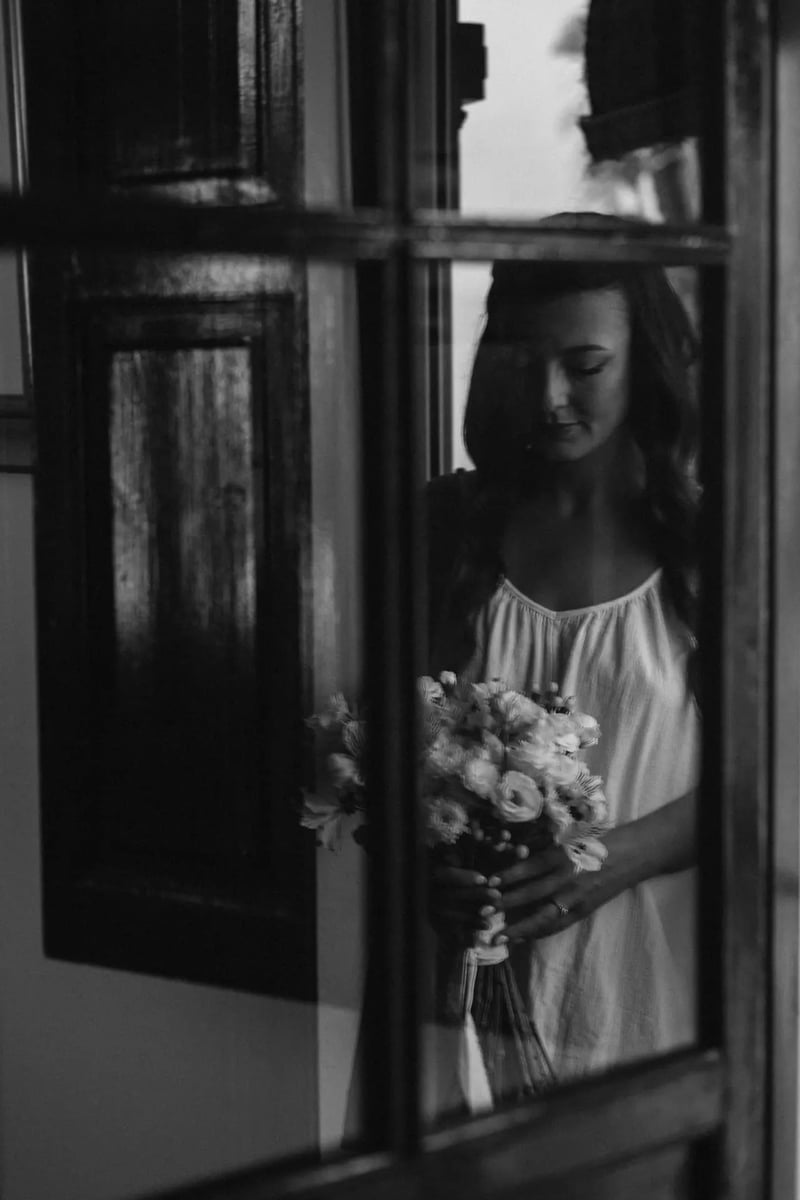 Rhianna con su ramo reflejada en la ventana, en blanco y negro – boda organizada por Greta Weddings