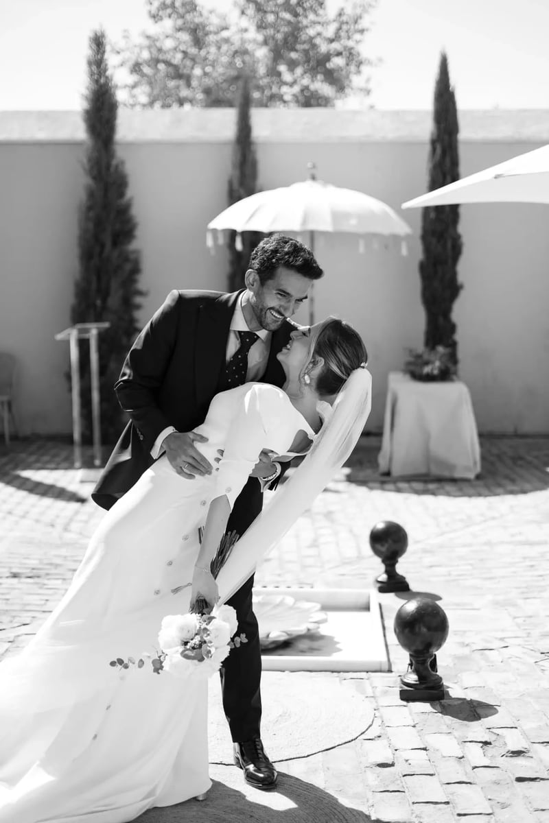 Luis besando a Aisha en volandas en el patio empedrado de la hacienda – boda organizada por Greta Weddings