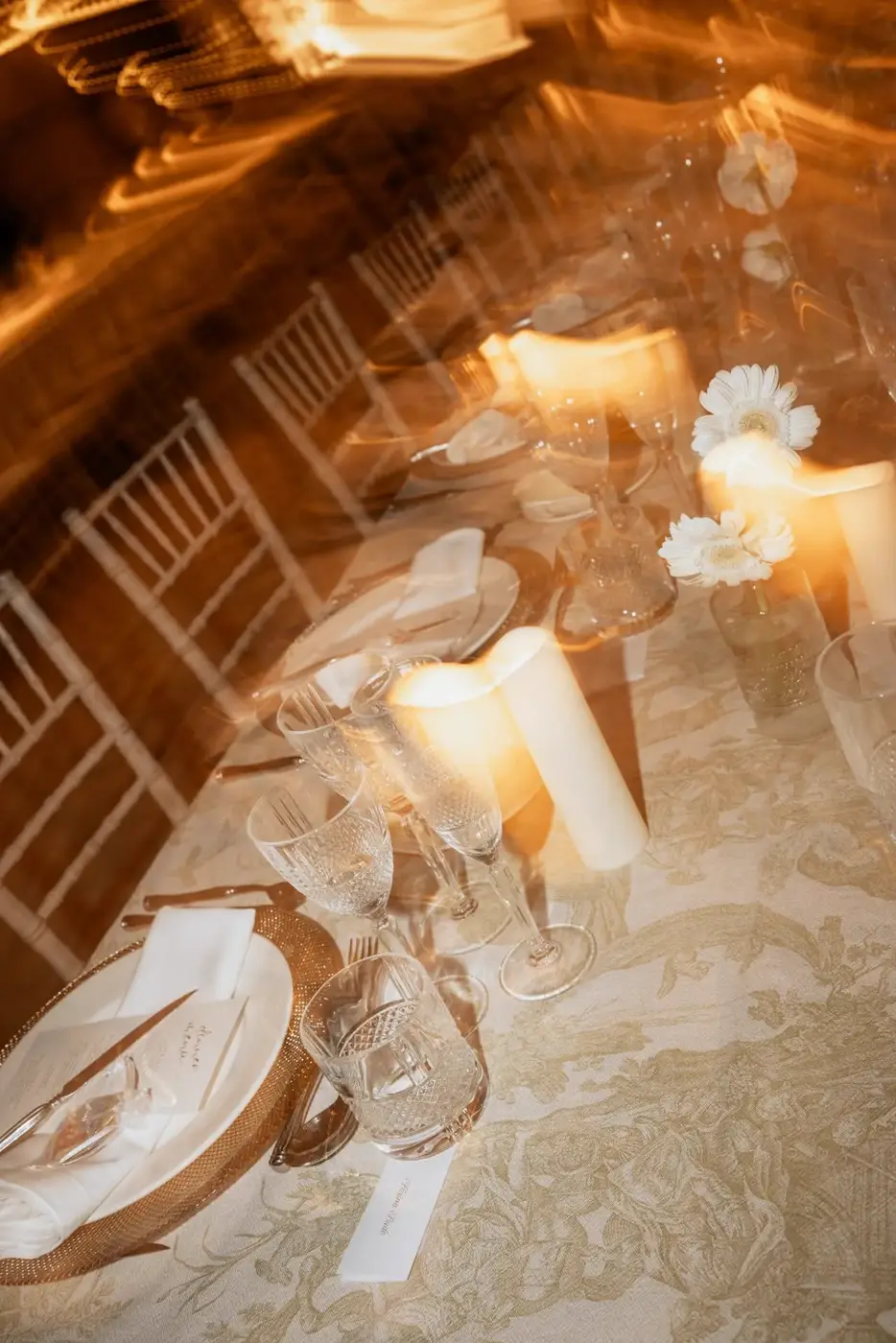 Detalle de la mesa con velas, gerberas blancas y minuta de cena
