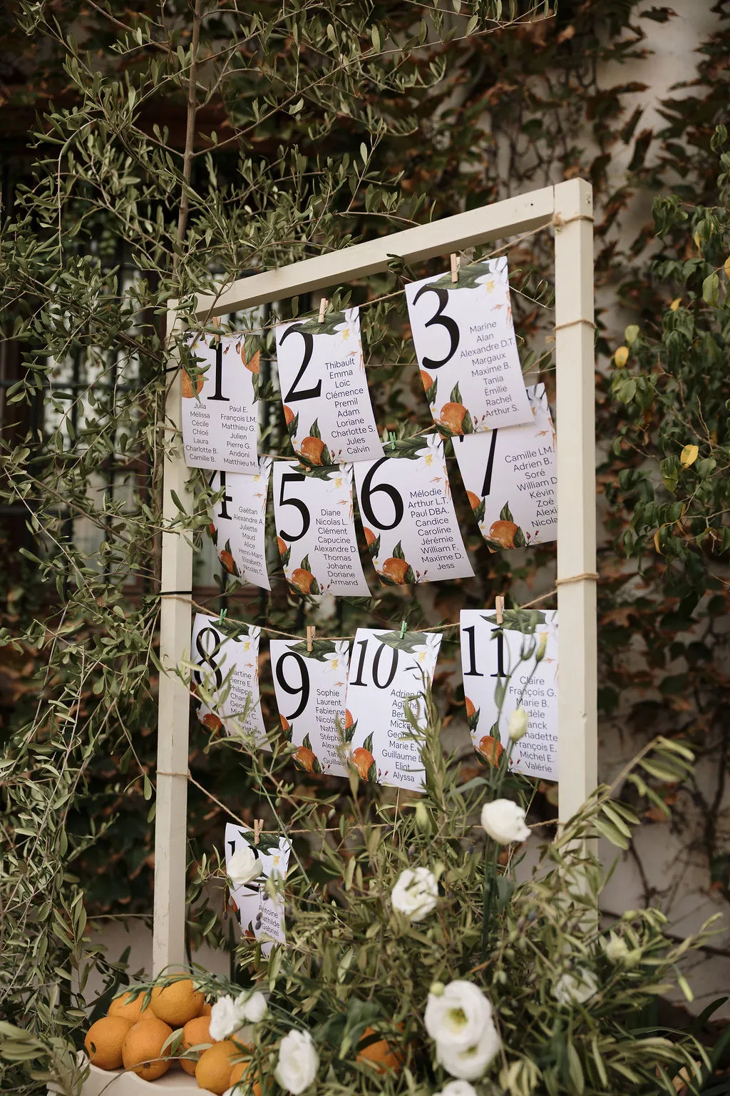 Seating plan con ramas de olivo, naranjas y flores blancas