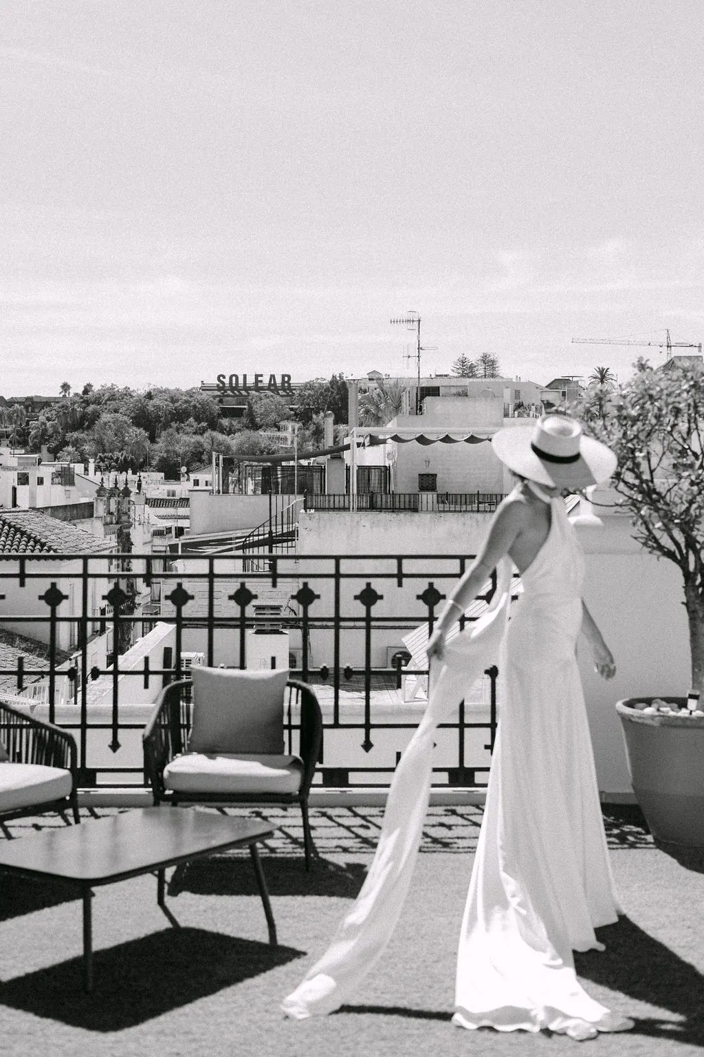 MªCarmen con su vestido y sombrero en una terraza de Sanlúcar de Barrameda, en blanco y negro