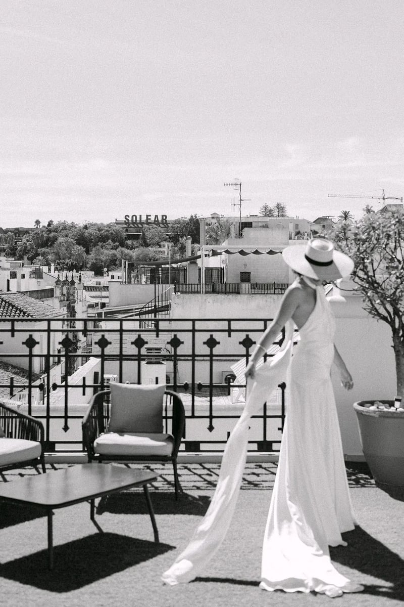 MªCarmen con su vestido y sombrero en una terraza de Sanlúcar de Barrameda, en blanco y negro – boda organizada por Greta Weddings