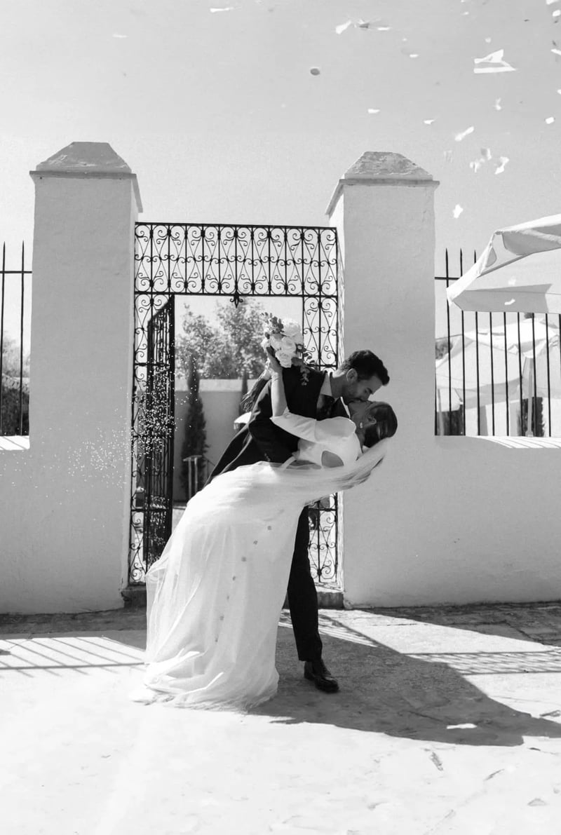 Luis besando a Aisha en volandas bajo una lluvia de pétalos en la puerta de la hacienda – boda organizada por Greta Weddings