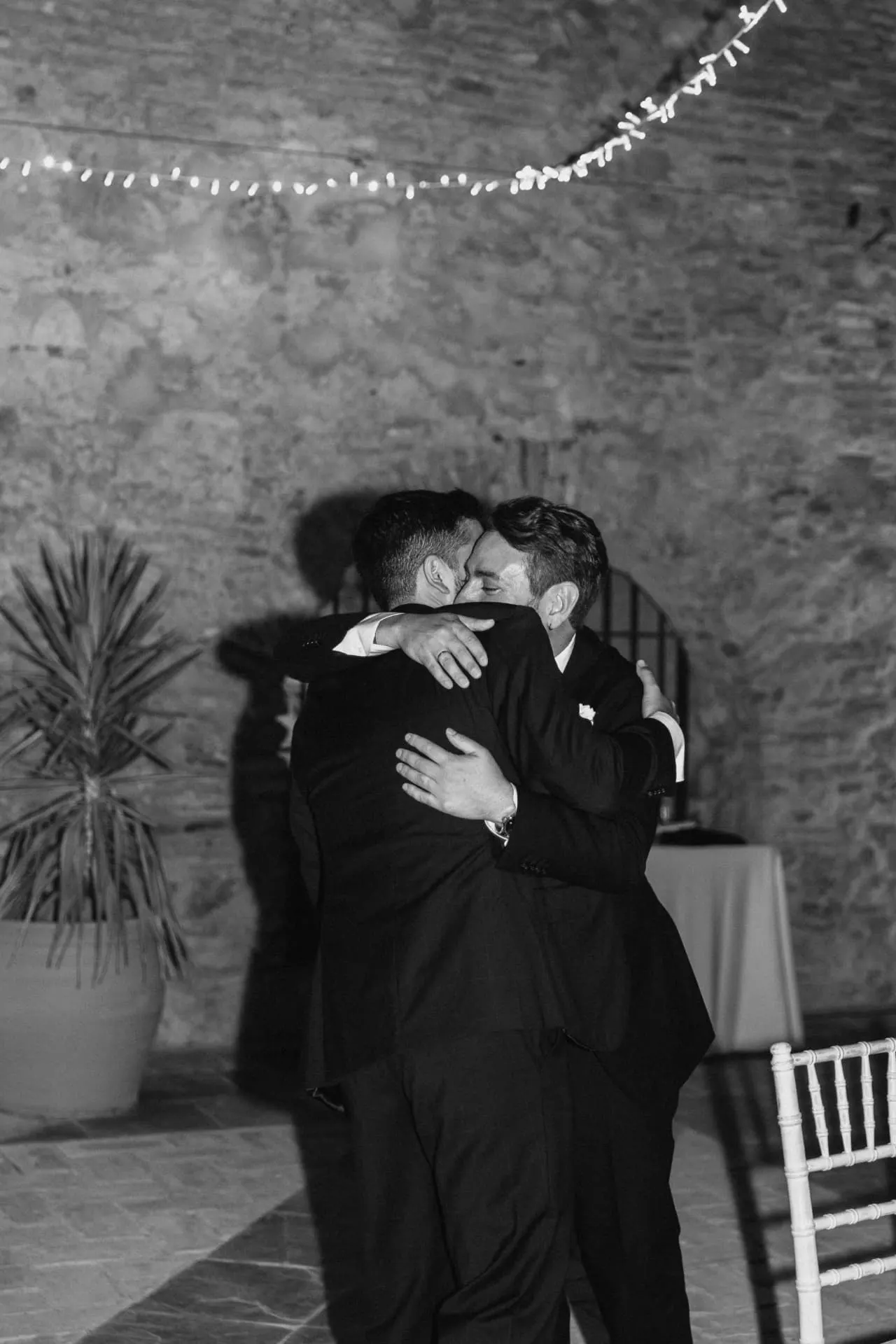 Abrazo emocionado entre Javier y un invitado, en blanco y negro