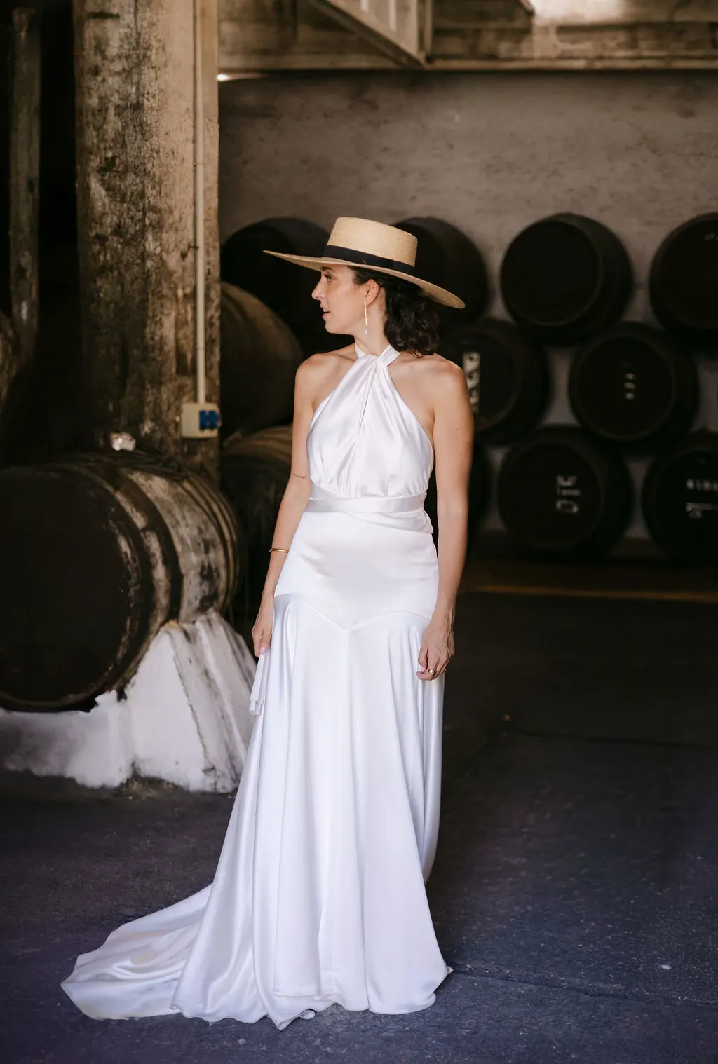 MªCarmen con su vestido de satén y sombrero entre las barricas de la bodega