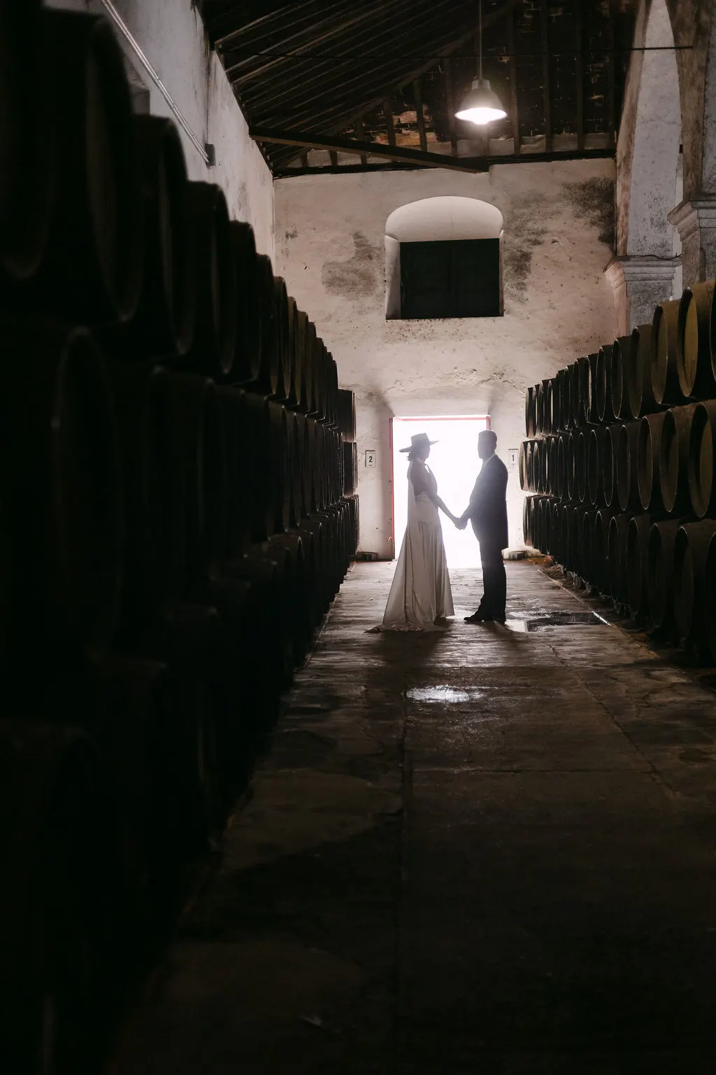 Siluetas de MªCarmen y Jose Miguel de la mano entre las botas de la bodega