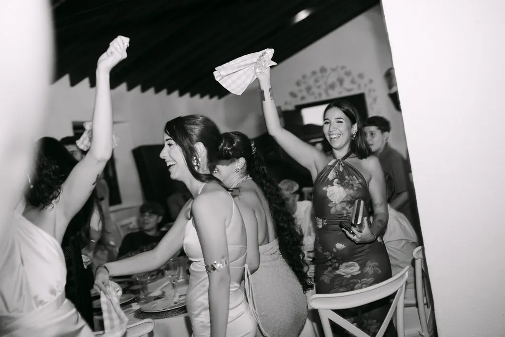 Invitadas celebrando con las servilletas en alto durante la fiesta, en blanco y negro